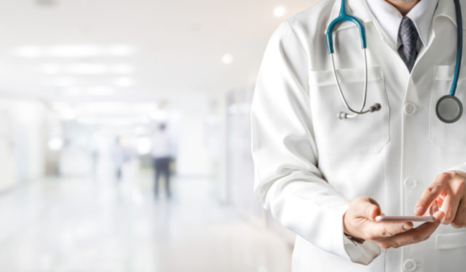 Male doctor using mobile phone at hospital. Medical healthcare and doctor service.